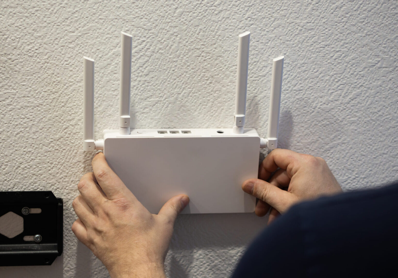 Hands installing a wireless router on wall.